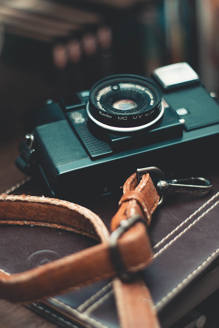 Close-up of a classic vintage camera with a leather strap placed on a notebook indoors.