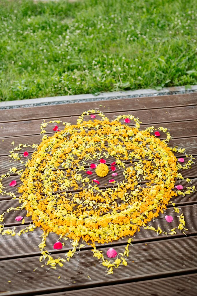 pexels photo 8818731 8818731 Beautiful yellow and pink flower petal rangoli on wooden deck, perfect for Diwali celebrations.